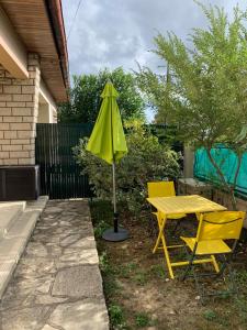 uma mesa amarela, duas cadeiras e um guarda-chuva em Lilas em Pessac