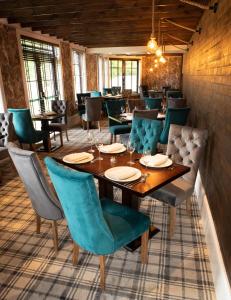 a restaurant with a wooden table and blue chairs at Crowwood Hotel and Alba Restaurant in Chryston