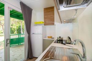Marina Julia Family Camping Village في مارينا جوليا: مطبخ مع مغسلة وثلاجة