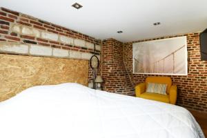 1 dormitorio con pared de ladrillo, cama y silla en MAISON VIEUX LILLE 3 chambres parking privé 24H24H Accès, en Lille