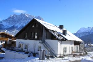 une maison dans la neige avec des montagnes en arrière-plan dans l'établissement Am Sonnenfels, à Lermoos