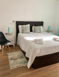 um quarto com uma cama grande e uma cadeira em Vila Verde em Castro Marim