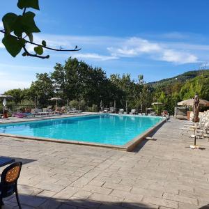a large blue swimming pool with chairs and umbrellas at Vakantiehuisje op park Ippotur in Castelnuovo Magra
