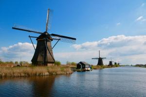 two windmills on a river with a house and a building at Trendy 2 bedroom accommodation on perfect location in Amsterdam
