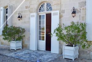 a white door and two potted plants on a building at Domaine de Gorre in Martillac