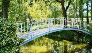 a white bridge over a river in a park at Domaine de Gorre in Martillac