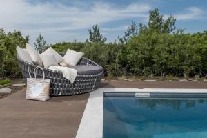 a wicker chair sitting next to a swimming pool at Alonella in Kefar Weradim