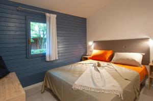 1 dormitorio con 1 cama con pared azul en Adriano Family Camping Village, en Punta Marina