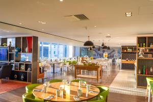 a restaurant with wooden tables and green chairs at Holiday Inn Liverpool City Centre by IHG in Liverpool