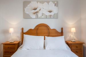 1 dormitorio con 1 cama con almohadas blancas y 2 lámparas en Apartamento cerca del Alcázar con garaje privado en Sevilla