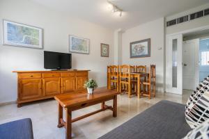 salon z telewizorem, stołem i krzesłami w obiekcie Apartamento cerca del Alcázar con garaje privado w Sewilli +7 zdjęć