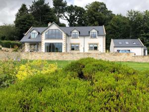 a house on a stone wall with bushes at Rothbury Hideaway in Rothbury