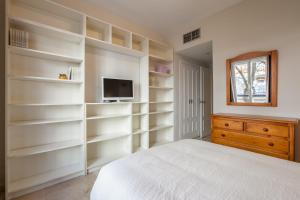 a bedroom with white shelves and a bed and a television at Apartamento cerca del Alcázar con garaje privado in Seville