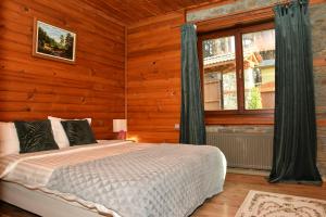 ein Schlafzimmer mit einem Bett in einem Zimmer mit Holzwänden in der Unterkunft Moiata Kashta Villa in Popovi Livadi