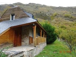 a building with a porch and a mountain in the background at LES CHALETS D'AURE. in Aragnouet