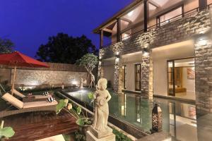 a home with a statue in front of a pool at Villa Kumuda by Nakula in Canggu