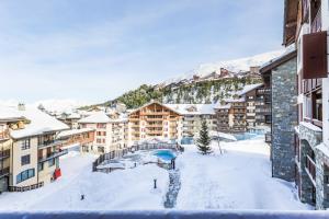 a resort in the snow with a bridge and buildings at Residence Arc 1950 Le Village - maeva Home in Arc 1950