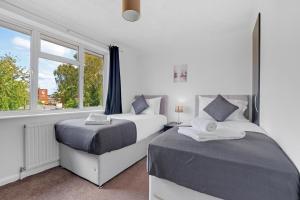 a bedroom with two beds and a window at Heathrow Living St Annes Serviced House 5 bedrooms 3 bath By 360Stays in Stanwell