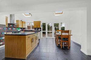 a large kitchen with wooden cabinets and a table at Heathrow Living St Annes Serviced House 5 bedrooms 3 bath By 360Stays in Stanwell