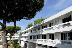 um edifício de apartamentos com varandas brancas e uma árvore em Actif Residence em La Grande-Motte