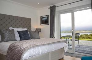 a bedroom with a bed and a balcony with a view at Woodland Lodge in Port na Long