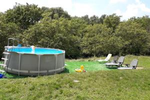 a hot tub in the grass with chairs and a person in it at Gîte st Julien des collines in Le Grand Serre