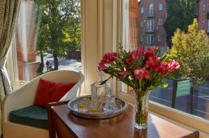 eine Vase mit Blumen auf einem Tisch vor einem Fenster in der Unterkunft Ravenhill House in Belfast