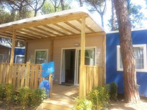 une petite maison avec un auvent sur une terrasse couverte dans l'établissement Adriano Family Camping Village, à Punta Marina