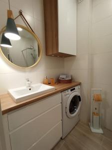 a bathroom with a sink and a washing machine at Apartamenty Września in Września