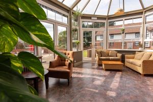 Dragonfly Hotel Bury St Edmunds في باري سانت ادموندز: حديقة شتوية مع كنب وكراسي وطاولة