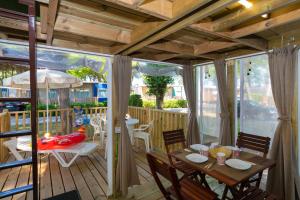 eine Terrasse mit einem Tisch und Stühlen auf einer Terrasse in der Unterkunft Adriano Family Camping Village in Punta Marina