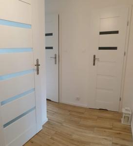 een kamer met twee witte deuren en een houten vloer bij Corso Nobile Apartament in Płock