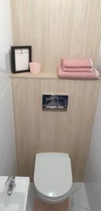 een badkamer met een wit toilet en roze handdoeken bij Corso Nobile Apartament in Płock