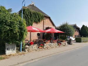 a restaurant with red umbrellas and flowers in front of a building at Gasthof-Ferienwohnungen-Kliesow´s Reuse in Alt Reddevitz