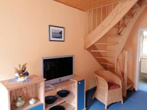 a living room with a tv and a staircase at Gasthof-Ferienwohnungen-Kliesow´s Reuse in Alt Reddevitz