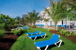 a group of blue lounge chairs on the grass near a hotel at Carousel Resort Hotel and Condominiums in Ocean City