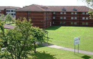 a large brick building with a sign in front of it at Yarnfield Park Training And Conference Centre in Stone