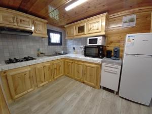 eine Küche mit Holzschränken und einem weißen Kühlschrank in der Unterkunft CASAMELIAS Le chalet in Cilaos