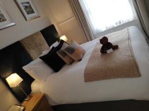 a teddy bear sitting on a bed in a bedroom at Clarence Court Hotel in Cheltenham