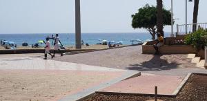 people walking on a beach with the ocean in the background at PLAYA LAS VISTAS LOFT in Los Cristianos