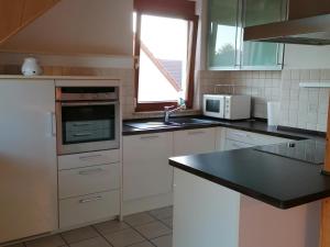 d'une cuisine avec des placards blancs, un évier et une fenêtre. dans l'établissement Ferienwohnung Suedbalkon, à Friesenheim