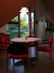 une salle à manger avec une table en bois et des chaises rouges dans l'établissement Ferienwohnung Suedbalkon, à Friesenheim