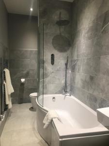 a bathroom with a bath tub and a toilet at Clarence Court Hotel in Cheltenham