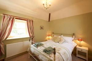 a bedroom with a bed and a window and a chandelier at Autumn Cottage in Kendal
