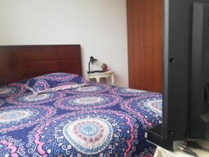 um quarto com uma cama com uma colcha colorida e uma televisão em Habitación con baño privado em Tunja