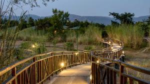 a wooden bridge with lights in a field at Vanaashrya Resort and Spa Sariska in Tehla