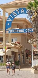 two people walking in front of a shopping center at PLAYA LAS VISTAS LOFT in Los Cristianos