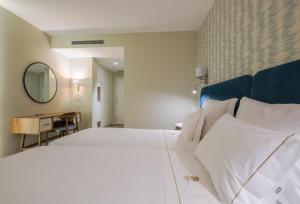 a bedroom with a large white bed and a desk at Hotel Vouga in Termas de Sao Pedro do Sul