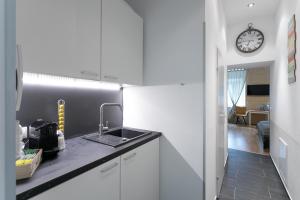 kuchnia ze zlewem i zegarem na ścianie w obiekcie Apartment, modern und neu renoviert w Wiedniu