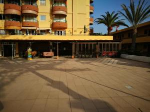 a large yellow building with palm trees and a fire hydrant at PLAYA LAS VISTAS LOFT in Los Cristianos